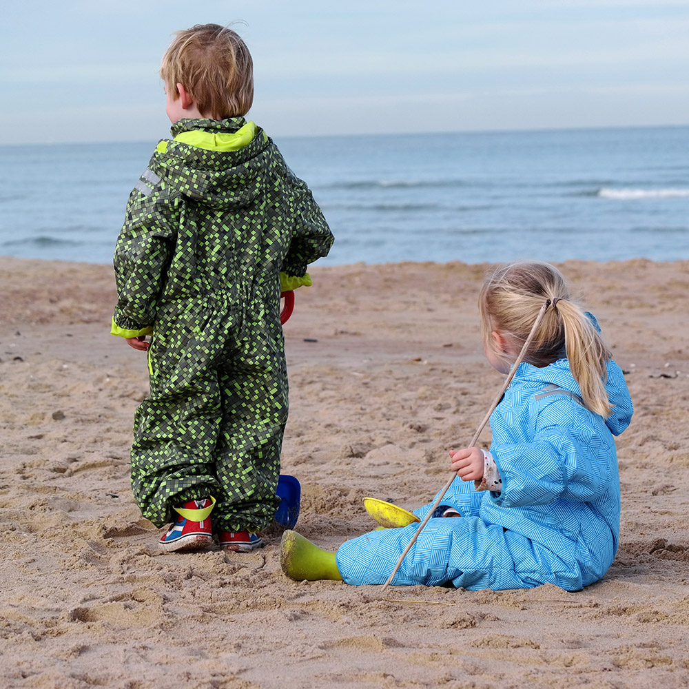 dzieci na plaży w kombinezonie chroniącym przed wiatrem, chłodem deszczem i mokrym piaskiem