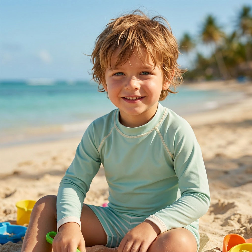 dziecko w rashguardzie UV bawi się na plaży